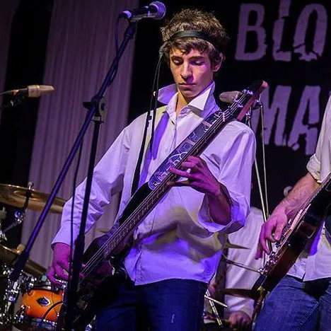 Sergio playing electric bass on stage with a band
